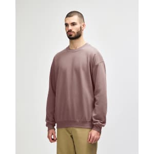 A softstyle adult sweatshirt in a mauve colour, featuring long sleeves and a relaxed fit. It has a logo.