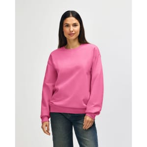 A pink Gildan Softstyle adult sweatshirt is worn by a model, paired with blue jeans. The sweatshirt has a logo.