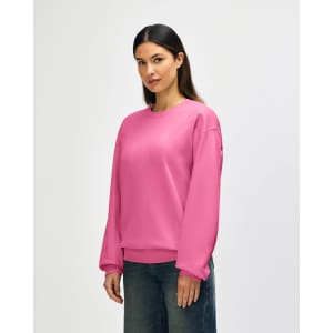 A pink Gildan Softstyle adult sweatshirt displayed on a model, featuring long sleeves and a crew neckline.