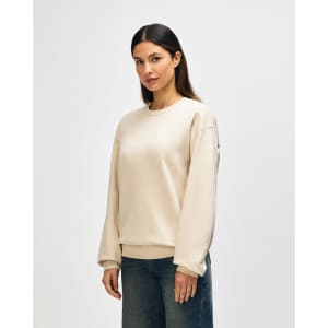 A beige Gildan Softstyle adult sweatshirt is displayed on a model, with a plain design and a visible logo.