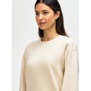 A beige Gildan Softstyle adult sweatshirt displayed on a model, featuring a classic crew neckline and long sleeves.