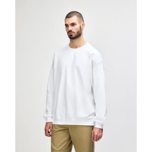 A white Gildan Softstyle adult sweatshirt displayed on a model, featuring a round neckline and long sleeves.