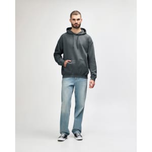 A green Gildan Softstyle adult hooded sweatshirt worn by a model, paired with dark jeans and sneakers.
