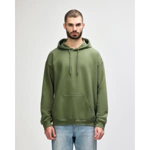 A woman wearing a green hooded sweatshirt with a front pocket and drawstring, standing against a plain background.