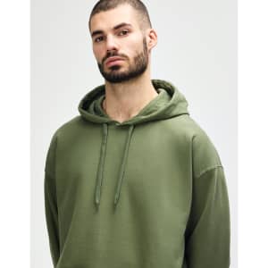 A model wearing a green Gildan Softstyle adult hooded sweatshirt, featuring a hood and drawstrings.