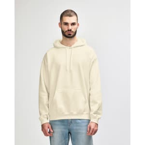 A cream-coloured hooded sweatshirt on a model, featuring a front pocket and a logo on the sleeve.