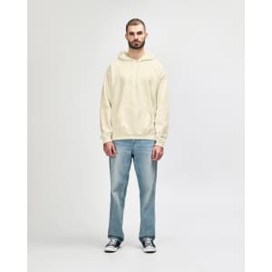 A hooded sweatshirt in cream, featuring a front pocket and a drawstring hood, modelled by a smiling man.