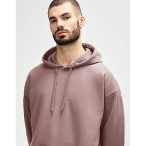 A woman wearing a pink Gildan Softstyle adult hooded sweatshirt, with her hands near the hood.