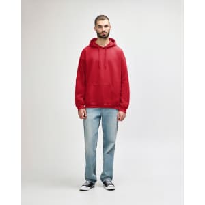 A red Gildan Softstyle adult hooded sweatshirt worn by a model, paired with blue jeans and white shoes.