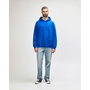 A blue adult hooded sweatshirt featuring a front pocket, worn by a model alongside black jeans and sneakers.