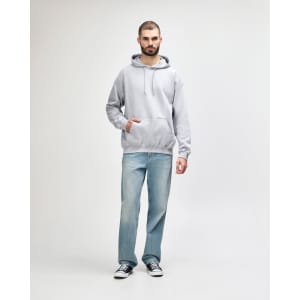A man stands wearing a grey Gildan Softstyle hooded sweatshirt and light blue jeans, with a logo on the sweatshirt.