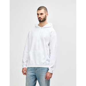 A white hooded sweatshirt with a relaxed fit, featuring a front pocket and a hood. The model is smiling and wearing denim jeans.
