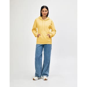 A yellow hooded sweatshirt worn by a model, paired with black jeans and sneakers, featuring a logo.