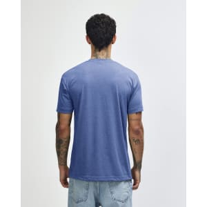 A blue American Apparel tri-blend T-shirt seen from the back, worn by a person with tattoos.
