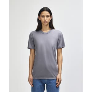 A grey American Apparel tri-blend T-shirt on a model, featuring short sleeves and a round neckline.
