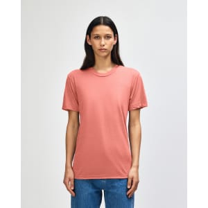 A person wearing a coral American Apparel tri-blend t-shirt, paired with blue jeans. The shirt has a logo.