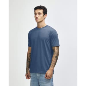 A blue tri-blend t-shirt displayed on a model with tattoos, featuring a simple design and no visible logos.