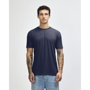 A navy American Apparel tri-blend T-shirt displayed on a model with tattoos, paired with light blue jeans.