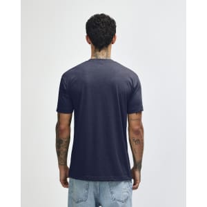 A navy American Apparel Tri-Blend T-shirt displayed from the back. The model has tattoos and wears light blue jeans.