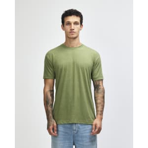 A man wearing an olive green American Apparel tri-blend T-shirt and blue jeans, standing against a plain background.