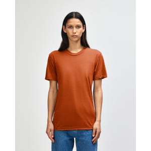 A model wearing an orange American Apparel tri-blend t-shirt, standing against a neutral background.