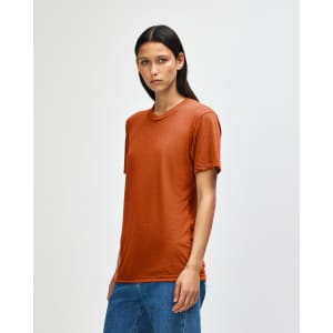A model wearing an orange American Apparel Tri-Blend T-Shirt, styled with blue jeans, displaying a casual look.