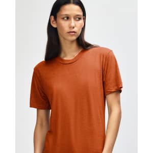 A model wears an orange American Apparel Tri-Blend T-Shirt, featuring a relaxed fit and a subtle texture.