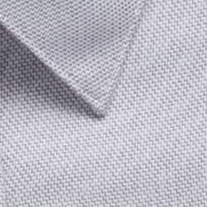 A close-up of a light grey woven fabric with a textured surface, featuring a collar edge and a logo.