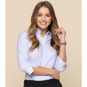 A button-up shirt in light blue, worn by a woman with long hair, smiling and posing against a neutral background.