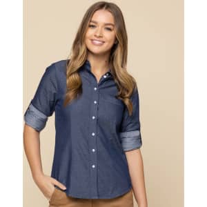 A button-up shirt in navy chambray with rolled-up sleeves, featuring a collar and buttons. Includes a logo.