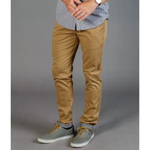 Tan chinos displayed on a model, featuring a slim fit and paired with grey shoes. The model wears a striped shirt.