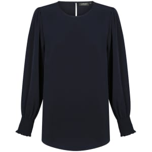 A navy blouse with a round neckline, long shirred cuffs, and subtle puffed sleeves. It features a keyhole opening at the back and a logo.