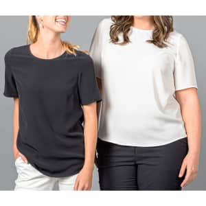 Two women wearing short sleeve shirts in black and white, standing side by side against a grey background.