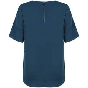 A short-sleeve shirt in a deep teal colour featuring a back zip closure and a rounded hem. It has a logo on it.