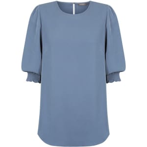 A blue blouse with shirred cuffs and a round neckline, featuring a subtle back opening and branding logo.