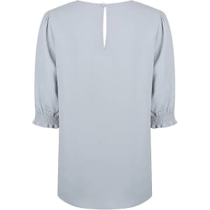 A light blue top with shirred cuffs and a keyhole back detail. It has a smooth, flowing design and includes branding.