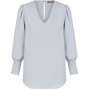 A light blue V-neck shirt with puff sleeves and smocked cuffs, featuring a back keyhole detail.
