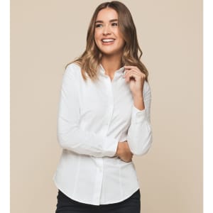 A woman in a white button-up shirt smiles, showcasing the Ashton Cotton Oxford Shirt. The shirt features a logo.