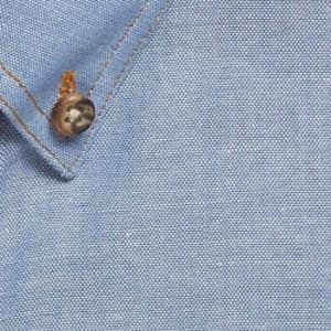 A blue work shirt featuring a buttoned collar and textured fabric. It has a logo on the side.