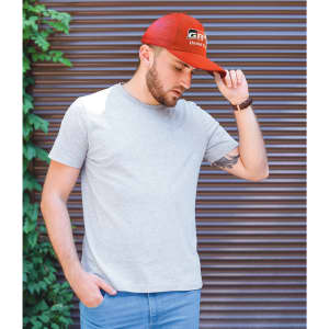 A red cap with tear drop perforations worn by a person in a grey t-shirt against a textured background.