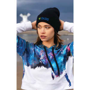 A young woman wearing a black beanie with a logo, paired with a colourful galaxy-patterned hoodie.
