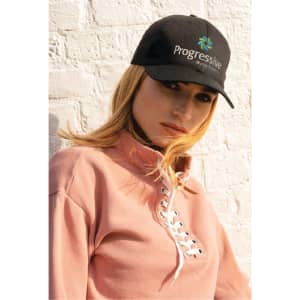 A black cotton cap featuring a logo, worn by a model in a pink top against a light brick background.