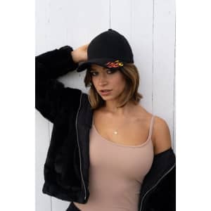 A black cap with sonic weld flame design, worn by a woman in a beige tank top and black jacket.