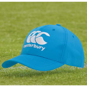A blue sports cap featuring an embroidered logo and a curved brim, positioned on green grass.