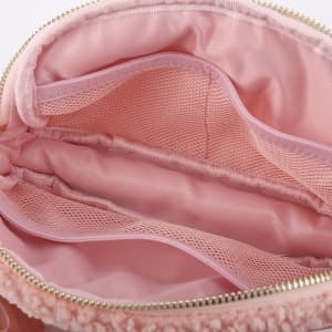 A pink fleece belt bag interior featuring mesh pockets and a smooth lining. The bag has a zipper and a branded logo.