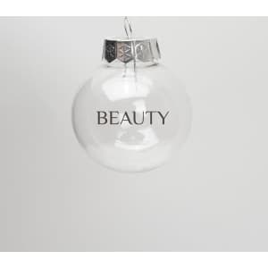 A clear plastic ball ornament with a silver cap and the word "BEAUTY" printed on it.