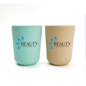 A set of two reusable coffee cups made from bamboo fibre, one in teal and one in beige, both featuring a logo.