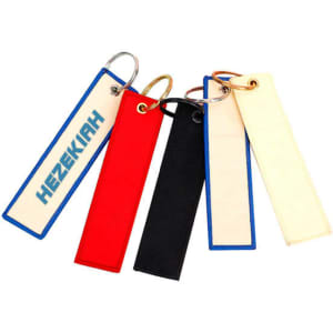 A set of custom embroidered keychains in red, black, white, and blue, featuring a logo on one.