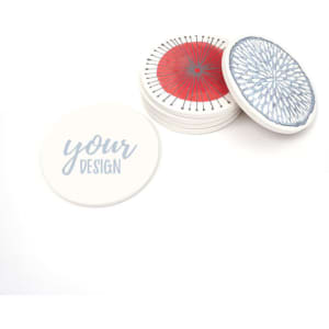 A set of absorbent ceramic coasters in white, featuring various designs in blue and red, with a cork base.