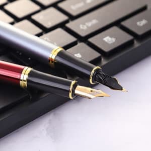 A custom fountain pen in silver and red, featuring gold trim, positioned alongside a black keyboard.